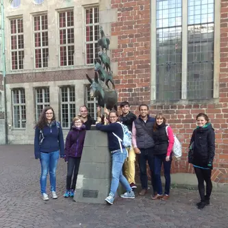Group photo of the participants of the seminar standing around the statue of the Bremen Town Musicians.