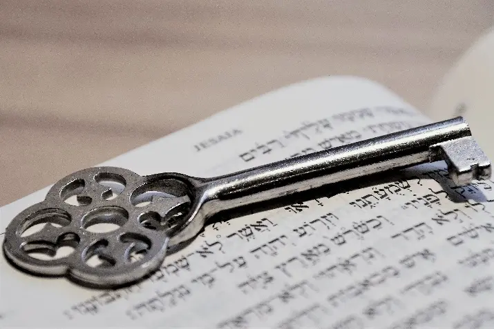 Alter Schlüssel, der auf einer hebräischen Bibel liegt.