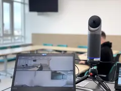 Blick in einen Seminarraum. Die Kamera (Kandao Meeting Pro) ist an einen Laptop angeschlossen. Im Hintergrund ist ein Seminarraum zu sehen.