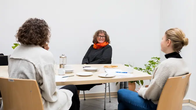 Maria Steger sitzt mit zwei Frauen an einem Tisch.