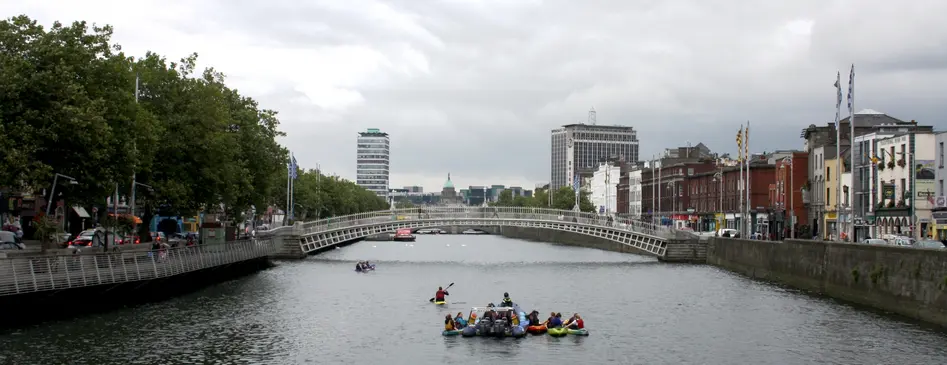 Photo of the River Liffey and the Millenium Bridge in Dublin in front of a grey sky.