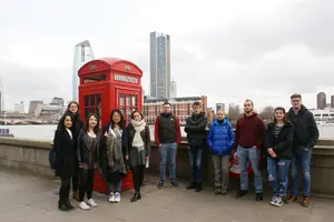 Group photo of the seminar members in front of a typical red phone booth with the London skyline in the background.
