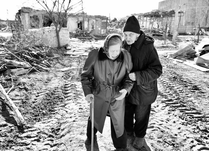 Zwei ältere Ukrainer stehen vor Trümmern.