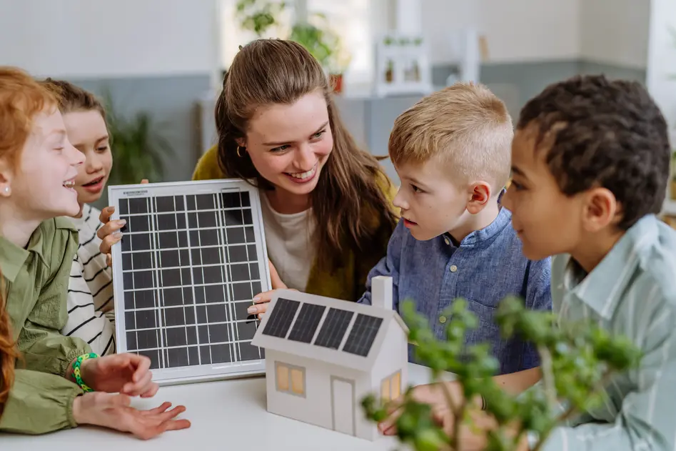 Young teacher with solar panel learning pupils about solar energy.