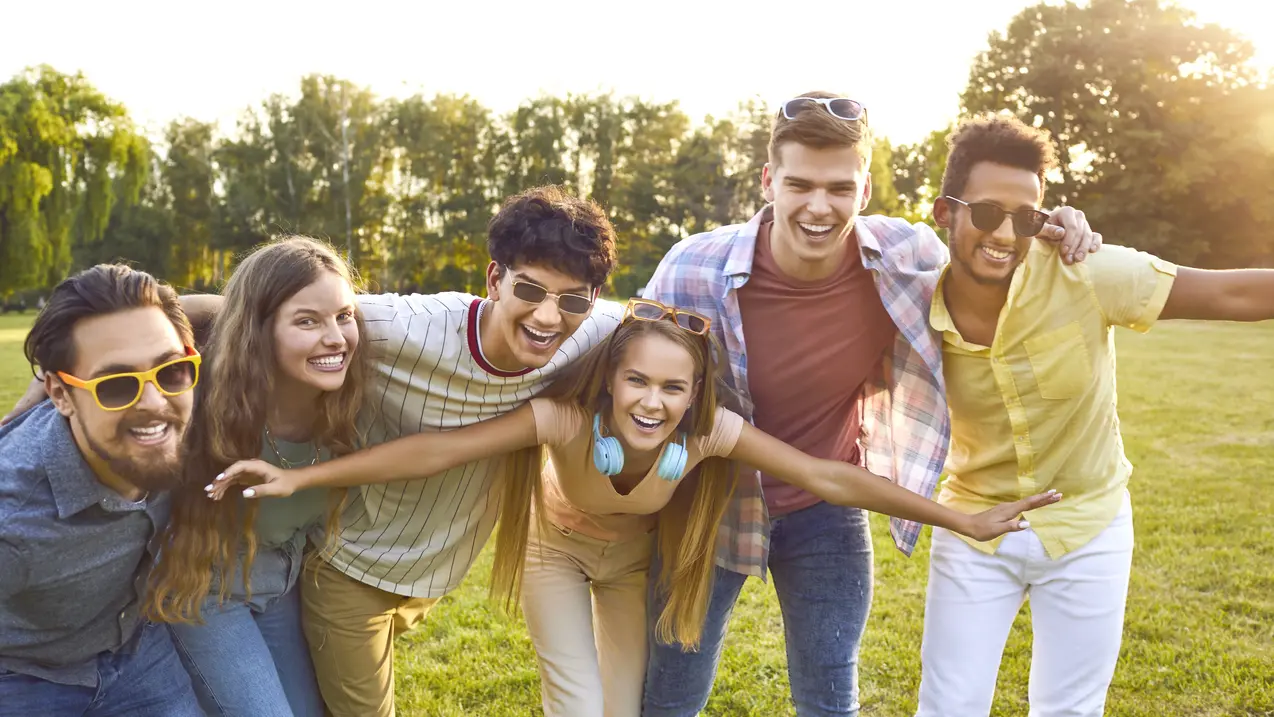 Group of happy, cheerful friends enjoying summer and having fun in the park together