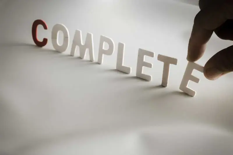 "COMPLETE"word made from colored wooden letters with human's finger