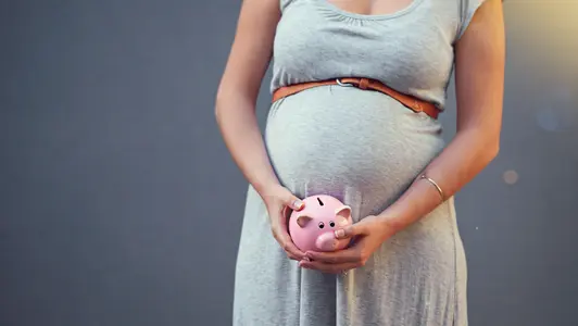 Pregnant woman, piggy bank and savings for newborn, baby and family investment or money, budget and planning for future finance. Pregnancy, mother and investing cash on studio gray background Schwangere Frau mit Sparschwein vor dem Bauch.