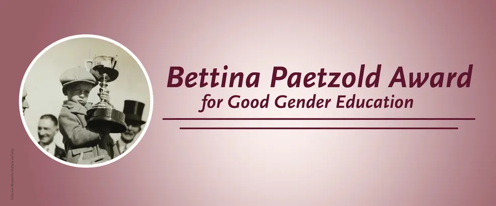 This is a banner with a pink background for the 'Bettina Paetzold Award for Good Gender Education' page. In a small, circular image, a child in a coat and cap can be seen proudly holding a large trophy in both hands. Several adults can be seen in the background, including a person wearing a top hat.
