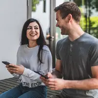 Zwei Personen mit Smartphones reden miteinander.