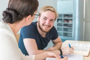 Zwei Studierende sitzen am Tisch und lernen gemeinsam