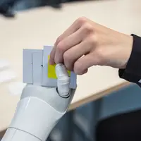 Roboter Pepper gibt einem Menschen eine Spielkarte.