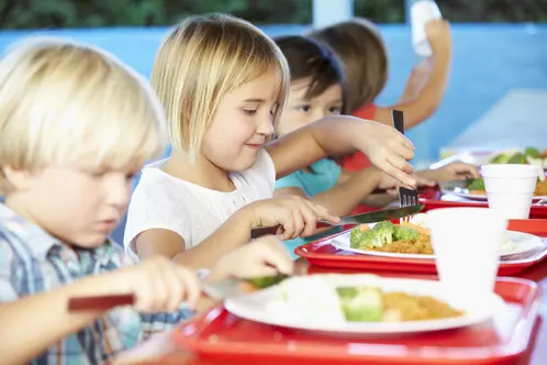 Elementary Pupils Enjoying Healthy Lunch In Cafeteria