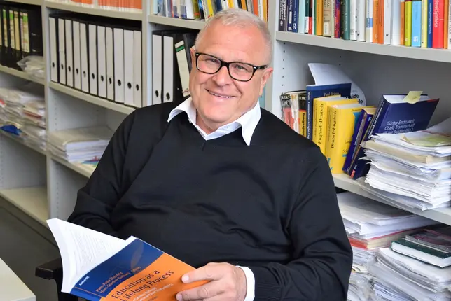 Hans-Peter Blossfeld, Professor an der Universität Bamberg, sitzt mit einer Publikation in seinem Büro - umgeben von Forschungsliteratur.