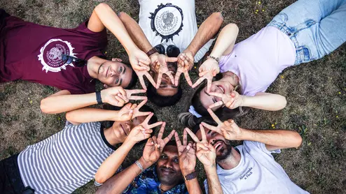 Studierende liegen gemeinsam auf der Wiese und bilden gemeinsam einen Stern