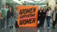 Gruppenfoto der Exkursion zu adidas mit einem Schild auf dem "Women supporting women" steht.