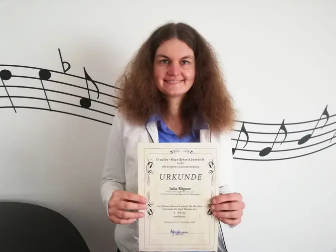 Julia Rögner mit Gewinnerurkunde des Irmler-Musikwettbewerbs der Universität Bamberg, Selbstporträt mi