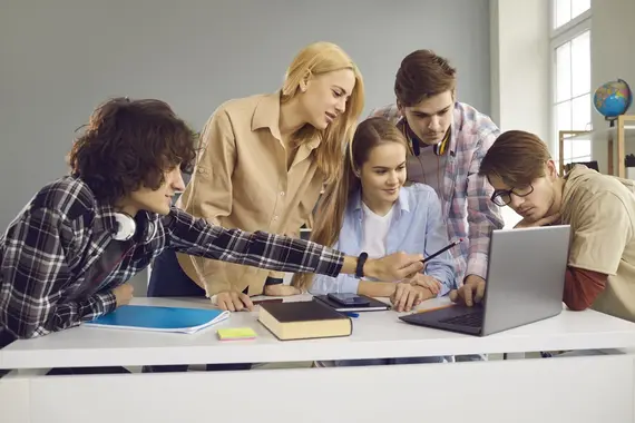 Creative school, college or university students working on group project and using laptop