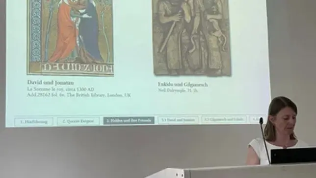 Prof. Dr. Kathrin Gies bei ihrer Antrittsvorlesung; im Hintergrund sind Bilder auf einer Präsentation zu sehen.
