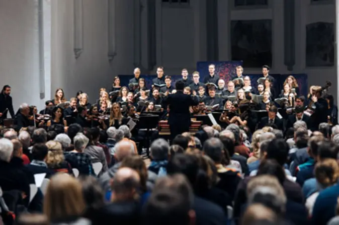 Kammerchor und -orchester der Universität Bamberg singen udn spielen im Chorraum der AULA vor Publikum.