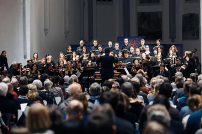 Kammerchor und -orchester der Universität Bamberg singen udn spielen im Chorraum der AULA vor Publikum.