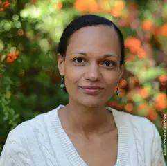 Das Foto zeigt die Autorin Regina Feldmann, eine Frau mit zusammengebundenen dunklen Haaren in einer weißen Strickjacke.