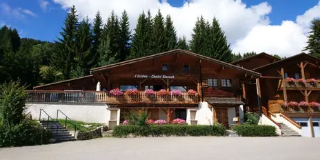 Photo of the accommodation. It is a big timber-framed house surrounded by big fir trees.