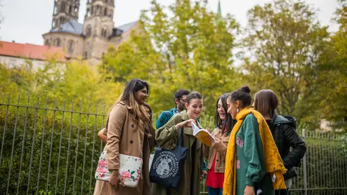 Studierende schauen draußen gemeinsam ins Buch