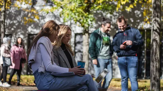 Studierende im Herbst vor dem Universitätsgebäude in der Feldkirchenstraße