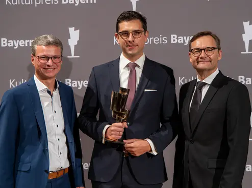 Bernd Sibler (l.) und Reimund Gotzel (r.) haben Christoph Weinert den Kulturpreis Bayern überreicht.
