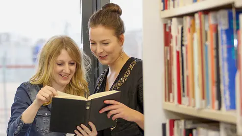 Students with books Studierende schauen gemeinsam in ein Buch in der Bibliothek