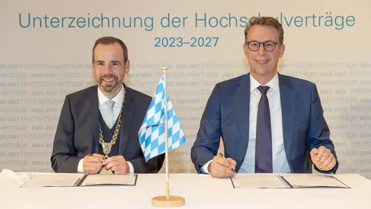Kai Fischbach sitzt neben Markus Blume, sie unterschreiben den Vertrag.