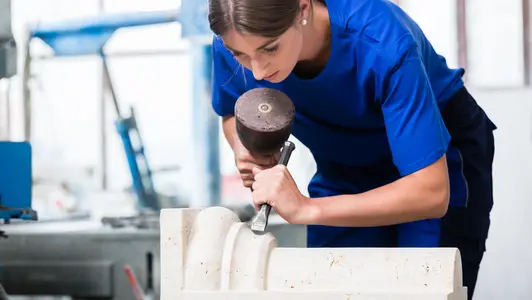 Eine junge Frau arbeitet mit Hammer und Meißel