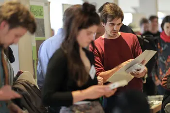 Bei einer Info-Messe im Rahmen der Nachhaltigkeitswoche an der Universität Bamberg blicken eine Besucherin und ein Besucher in Informationsmaterialien.  