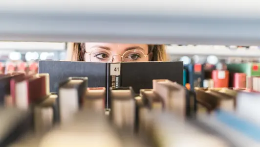 Person hinter Bücherregal
