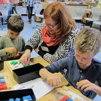 Eine Mitarbeiterin der Universität Bamberg erklärt zwei Kindern Pixel mithilfe eines Puzzles.