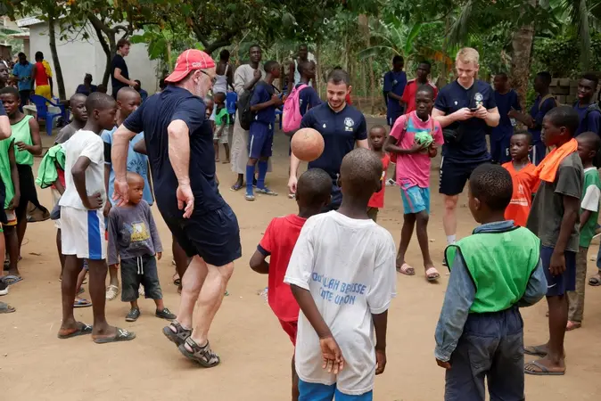 Otto J. Band und seine Auswahlmannschaft spielen mit Kindern an der Elfenbeinküste Fußball.