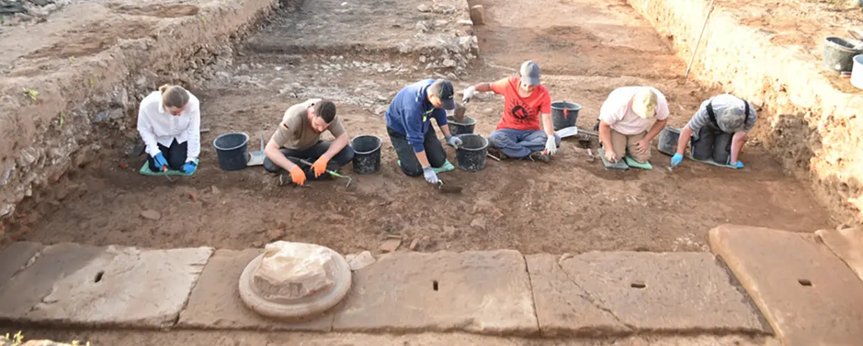 Studierende Graben den Eingangsbereich eines massiven römsichen Steingebäudes aus