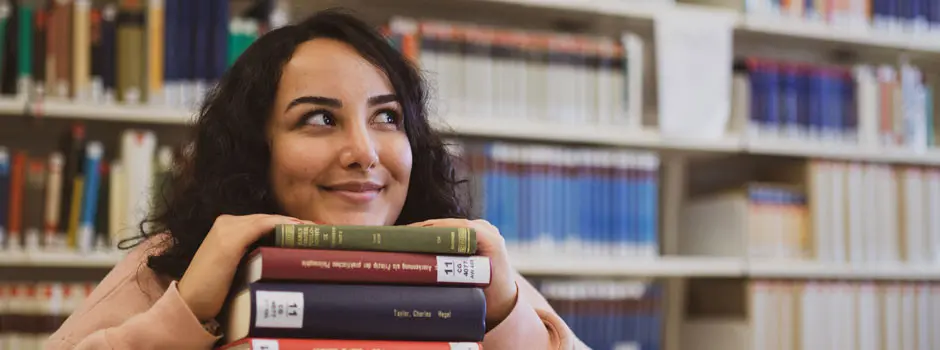 Eine glückliche Studentin sitzt in der Bibliothek
