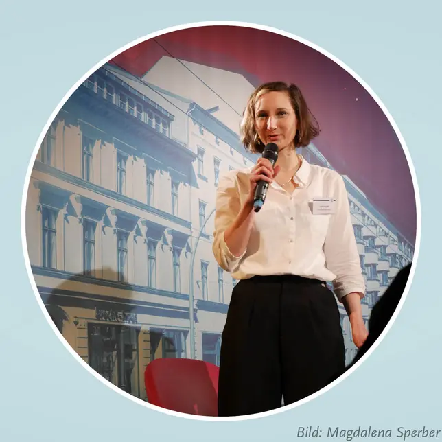 Rednerin mit Mikrofon auf der Tagungsbühne