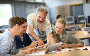 Lehrer mit einer Gruppe Schülern, die an Tablets arbeiten