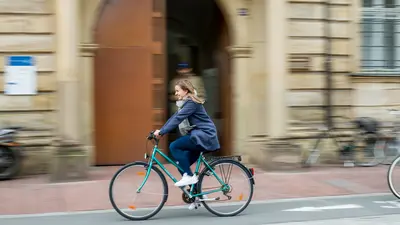 Radfahrerin vor dem Universitätsgebäude Kapuzinerstraße 25