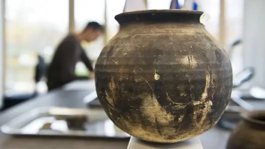 Eine alte Vase steht auf einem Tisch.