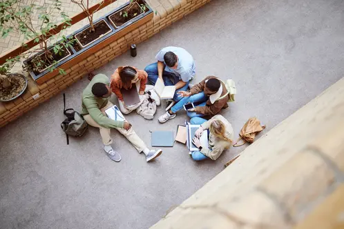 University, group collaboration and students working on research, college project or education study. Knowledge learning, teamwork meeting and top view of diversity people coworking on school floor