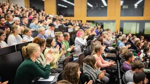 The photo shows parts oft he applauding audience at the end of David Frum’s lecture. It is taken from the left side of the room.