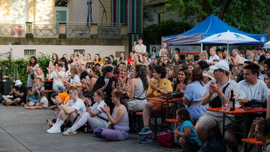 Zahlreiche Menschen sitzen vor der Bühne beim uni.fest