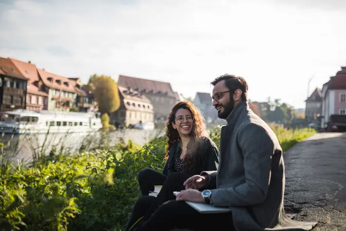 Zwei Studierende sitzen vor Klein-Venedig in Bamberg.