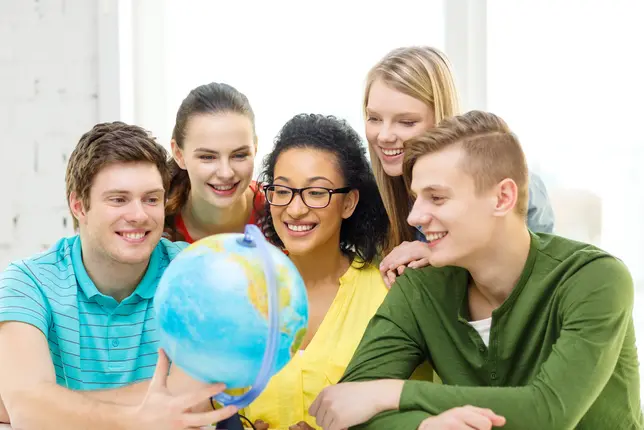 Das Foto zeigt eine Gruppe von fünf Studierenden, die um einen Globus versammelt sind. Darunter zwei Männer und drei Frauen. Die Männer und zwei der Frauen sind weiß. Die Dritte Frau ist eine Person of Color.