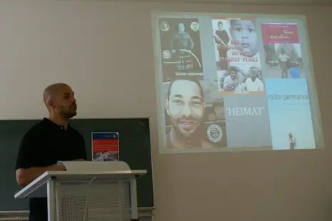 Cedric Essi delivering his guest lecture "The Allure of Diasporic Homecoming: Barack Obama's Dreams from My Father and Ika Hügel-Marshall's Daheim Unterwegs".