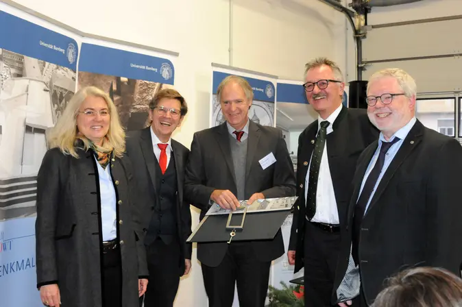 Rainer Drewello (Mitte), Dagmar Steuer-Flieser, Kanzlerin der Universität, Jürgen König, Leiter des Staatlichen Bauamts Bamberg, Peter Müller, ehemaliger Amtschef des Bayerischen Staatsministeriums für Bildung und Kultus, Wissenschaft und Kunst, sowie dem ehemaligen Universitätspräsidenten Godehard Ruppert (v.l.n.r.).