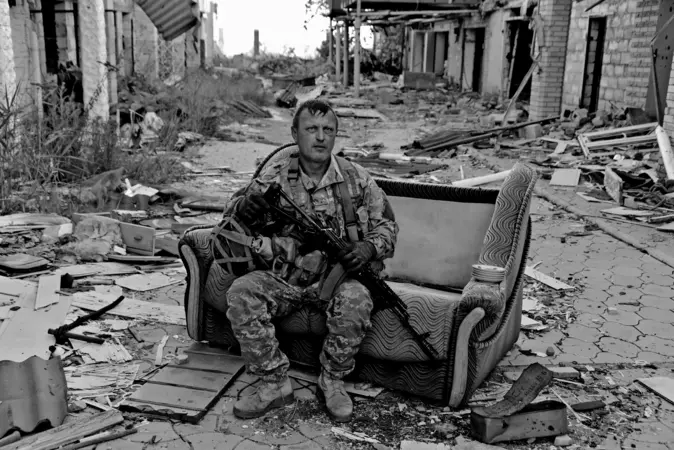 Ein Soldat sitzt auf einer Couch, umgeben von Ruinen